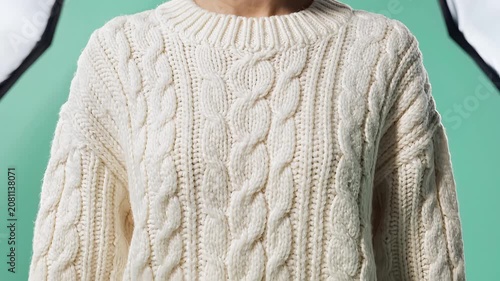 Cream cable knit sweater textured close up on light green background