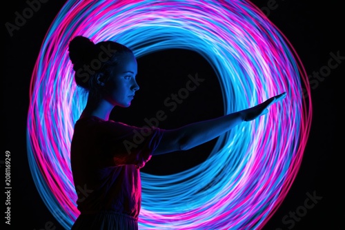 Silhouette of a woman standing in profile with a glowing neon circle light art