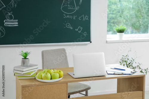 Apples and laptop on teache...