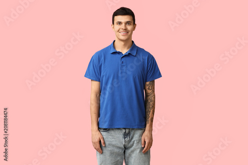 Handsome young man in stylish blue t-shirt on pink background