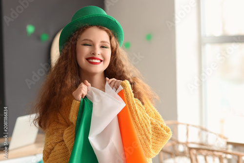 Young woman with flag of Ireland celebrating St. Patricks Day in kitchen