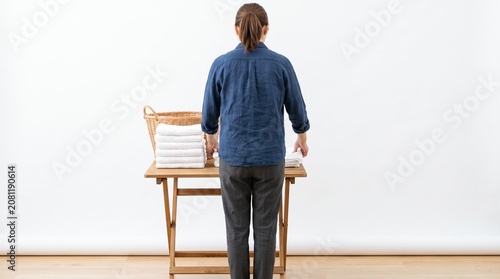 Photorealistic person from side, no face visible, folding towels neatly, bathroom chore, white seamless background
