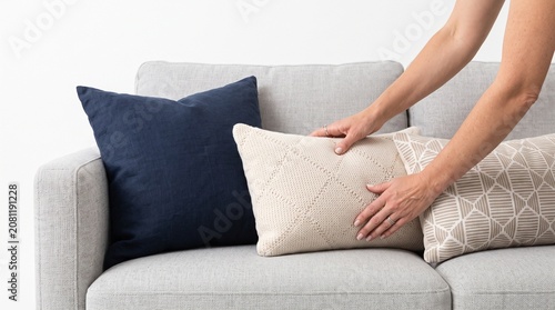 Photorealistic hands arranging pillows on sofa, neat adjustment, no face, pure white seamless background