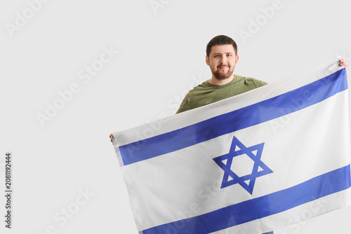 Schilderij op canvas Young Jewish man with flag of Israel on light background