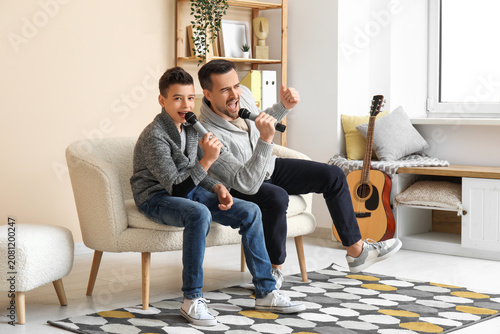 Father and his little son with microphones singing at home