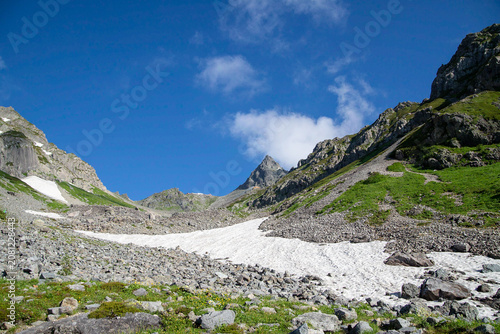 Fotografie Rocky alpine valley with summer snowfield and mountain peaks, Japanese Alps