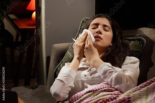 Tablou pe pânză young woman on sofa covered with a blanket freezing blowing running nose got fev