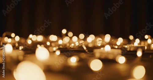 Decorative tea candles glowing with golden bokeh fairy lights at night