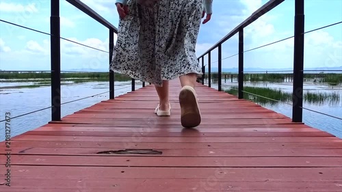 A girl walks across a bridge in the middle of a lake, close-up