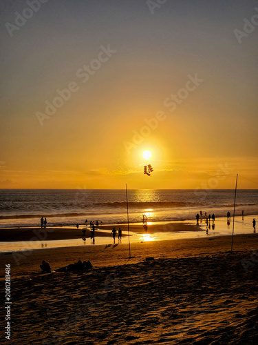 Golden sunset over a sandy beach with silhouettes of people