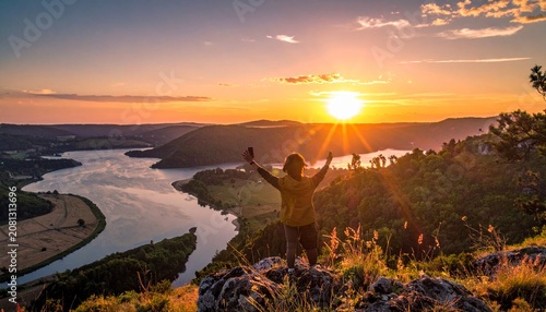 Person Embracing the Sunrise Over a Winding River Landscape.