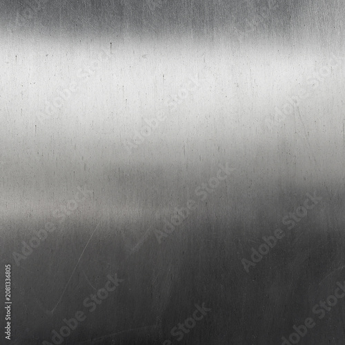 Scratched Brushed Metal Texture Background with Gradient Light. A weathered metal surface featuring light streaks, scratches and a subtle gradient transition, for industrial design or tech backdrops.