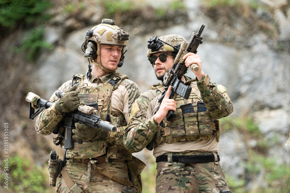Fototapeta premium Military personnel discuss equipment and mission details during a tactical field briefing