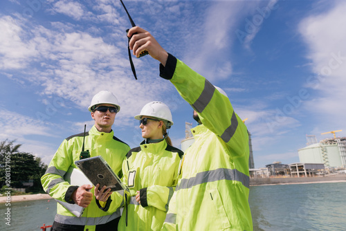 Engineers collaborating at oil and gas refinery analyzing data and ensuring safety protocols in industrial environment
