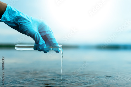 Scientist collecting water sample to monitor pollution and environmental quality.