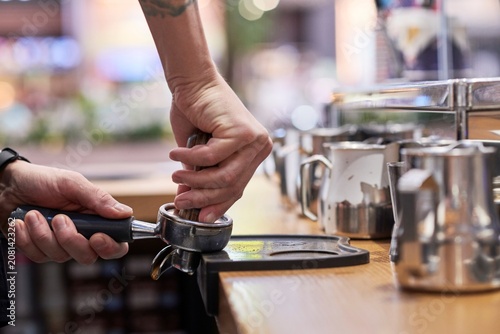 Photography Barista tamping ground coffee in portafilter, espresso preparation close-up, cof