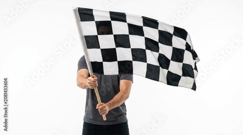 A person holds a black and white checkered flag, commonly known as a checkered flag, which symbolizes the finish line or the end of a race. The flag is being waved by someone.