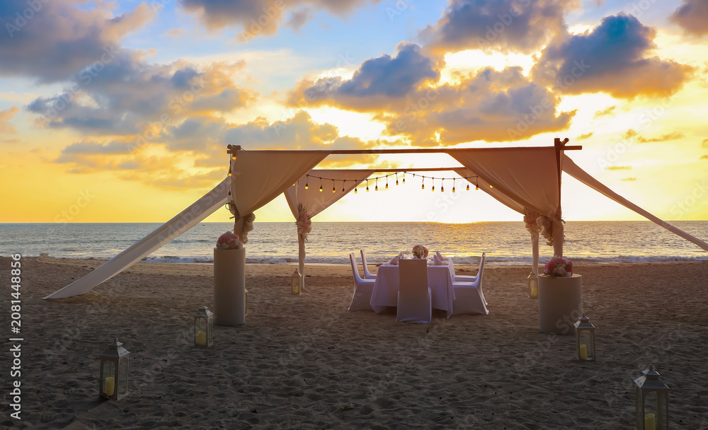 Fototapeta premium Romantic dinner table setting on the beach at sunset view scene with romantic scene of dinner set up background