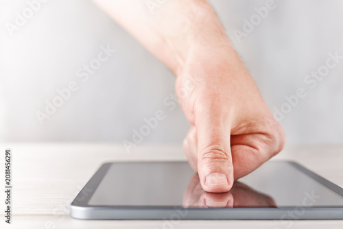 Hand touching digital tablet screen on light table with soft background, modern business technology concept for digital trust, data privacy, cybersecurity, secure access, user authentication, online