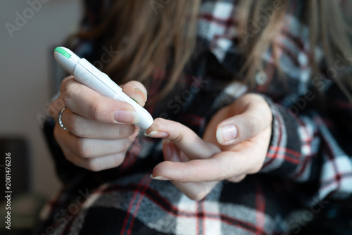 Foto Close-up of a girl using a lancing device to prick her finger for a blood sugar test
