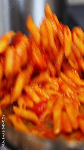close-up of stir frying penne pasta pan. Cinematic slow motion video of cooking macaroni in an Italian restaurant.