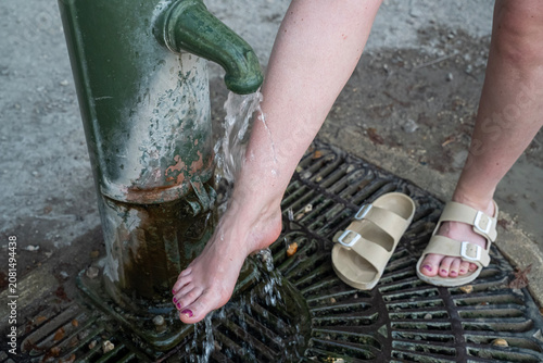 osoba chłodząca stopy zimną wodą z hydrantu miejskiego w upalny letni dzień