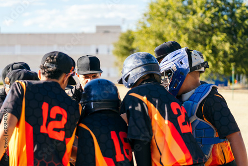 Fotografie Youth baseball team players and coach gathering in a huddle, discussing game str