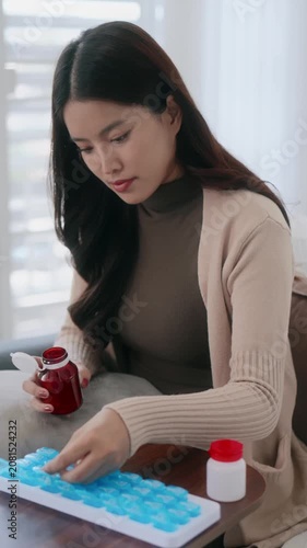 Asian woman organizing pills in a pill box for preparing daily routine medication