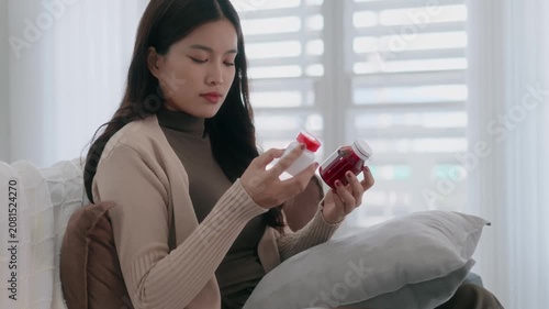 Asian woman checking on medicine bottle at home