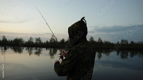 Silhouette of Angler Casting Line at Dusk on Calm Forest Lake