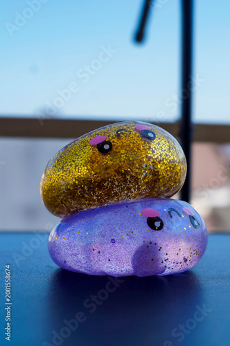 Two glittery squishy toys with cute faces are stacked on a tabletop by the window. Sensory play concept for tactile exploration, relaxation and playful emotions