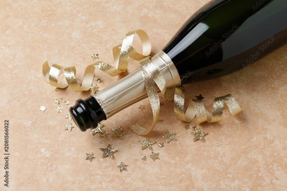 Fototapeta premium The Champagne Bottle Celebration with Ribbon and Star Confetti on Decorated Surface