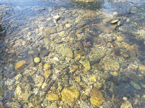 Plano detallado de agua cristalina y fondo de cantos rodados en la piscina natural de Hoyos, Sierra de Gata, Cáceres, España.
