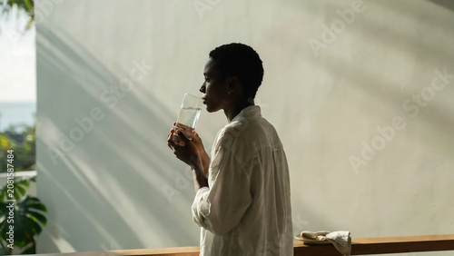 Young woman relaxing and drinking water by a bright window