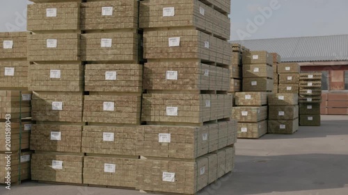 Large stacks of bundled wood planks stored in an open-air lumber yard under a cloudy sky, ready for transport, distribution, or construction use