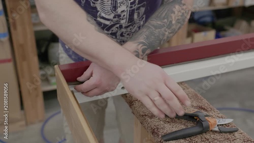 Close-up of a worker fitting sealing insulation into a painted wood window frame during factory assembly