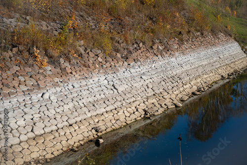 Stone hexagonal block revetment along a historic canal embankment.