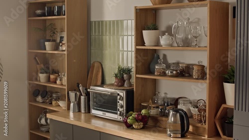 No people shot of kitchen counter displaying wooden shelves, electric kettle, toaster oven, and fresh apples. Clip serving as background for home appliance ads or interior design promotional videos