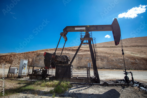 Oil Pumpjack in Dry Rural Landscape Under Blue Sky – Petroleum Extraction and Fossil Energy Industry Concept