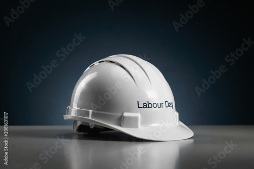 Striking three dimensional metallic silver text spelling Labour Day against a dynamic backdrop of abstract flowing industrial steel metal waves with visible rivets and intricate patterns