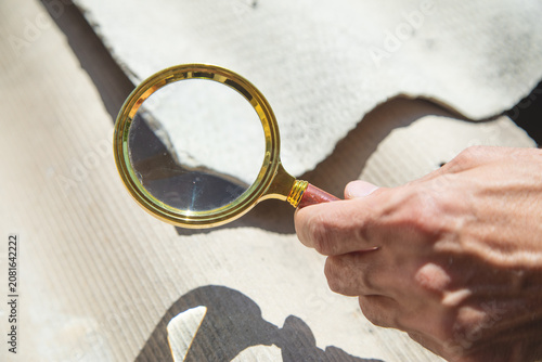 Male hand with a magnifying glass showing old asbestos roof. Health problems