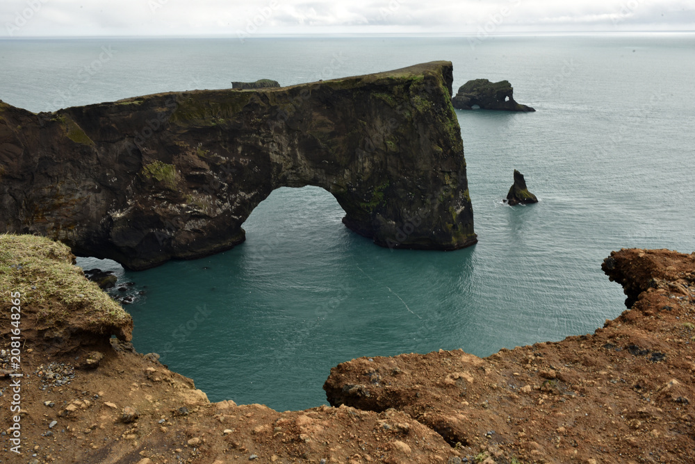 Fototapeta premium Massive stone arch of Dyrholaey peninsula rising from the sea, Iceland