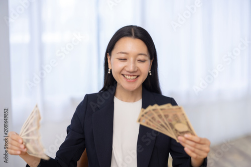Tablou pe pânză Young Japanese woman holding 100000 yen smiling at camera