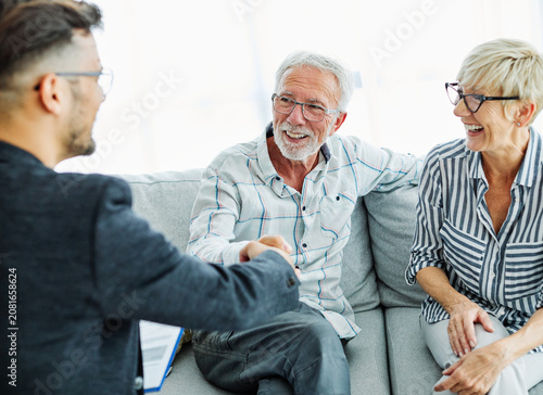 Happy senior old family couple clients make financial insurance estate business deal handshake agent lawyer, satisfied mature customers shake hand meeting bank manager agree on investment contract