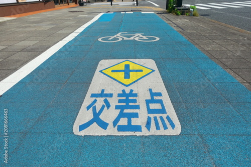 道路上の自転車専用通行帯と「交差点」の路面標示。交通ルールと安全意識の啓発イメージ。