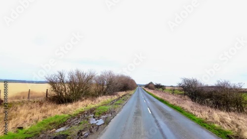 Driving dash cam style footage along quiet rural back roads in North Yorkshire England during the winter passing dry stone walls woodland and winding countryside roads with scenic landscapes