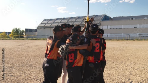 Youth baseball players celebrating victory. The team huddles together, jumping and hugging on the field in a display of teamwork and joy
