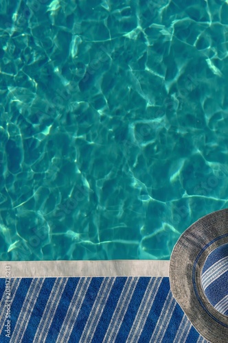 Enjoying a Sunny Day by the Poolside With Water and a Straw Hat