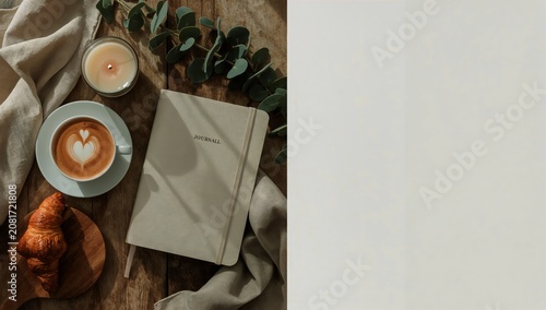 Coffee Cup and Journal on a Wooden Table With a Croissant and Candle in a Coz...