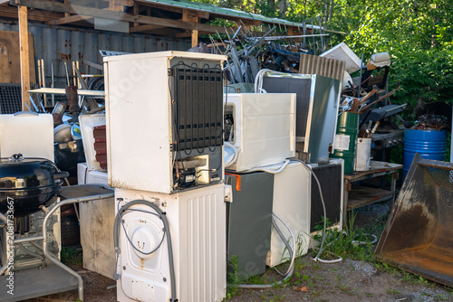Discarded household appliances and electronic waste at outdoor recycling center awaiting processing